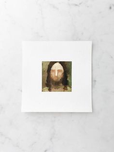 a white card with a painting of jesus's face on the front and bottom