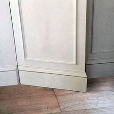 a cat sitting on the floor in front of a white door with an open top