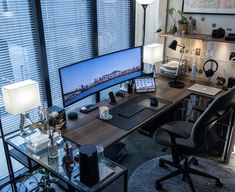 a desk with a computer monitor, keyboard and mouse on it in front of windows