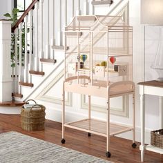 a white bird cage sitting on top of a wooden floor next to a stair case