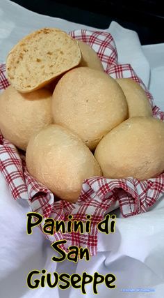 a basket filled with bread sitting on top of a white tablecloth covered table next to a red and white checkered napkin