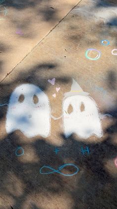 two ghost faces drawn on the sidewalk with colored chalks and confetti around them