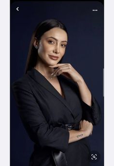 a woman posing for the camera with her hand on her chin and wearing a black jacket