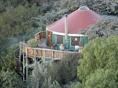 a tree house in the middle of trees with people sitting on it's deck