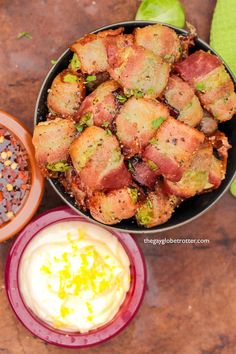 a pan filled with meat and vegetables on top of a wooden table next to other foods