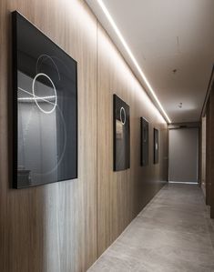 a long hallway with pictures on the wall and artwork hanging up against the wood paneling