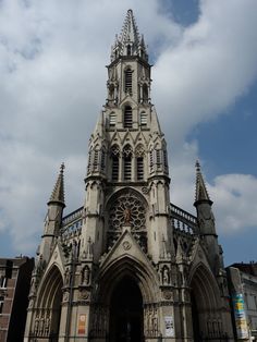 a large cathedral with a clock on it's side and sky in the background