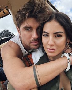 a man and woman are posing for a photo in a convertible car with their arms around each other