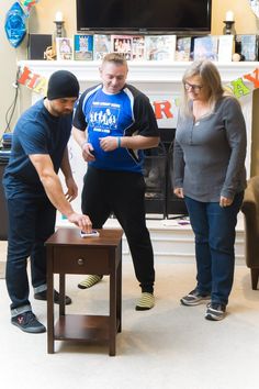 three people standing around a table in front of a tv