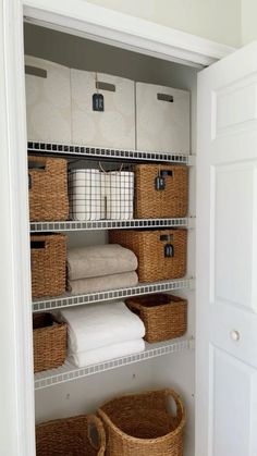 an organized closet with baskets and towels