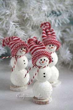 three snowmen with hats and candy canes in front of a white christmas tree