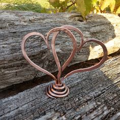 a metal heart sculpture sitting on top of a piece of wood