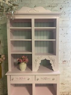 a pink china cabinet with flowers on top