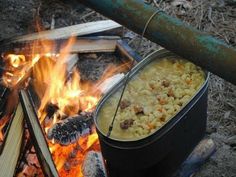 a pot filled with food sitting on top of a fire