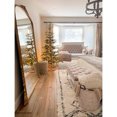 a bedroom decorated for christmas with a bed, mirror and couch in the corner next to it