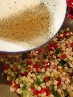 a bowl filled with corn and seasoning being poured into it