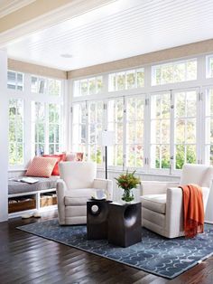 a living room filled with white furniture and lots of window sill space next to a couch