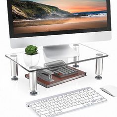 a computer monitor sitting on top of a glass desk next to a keyboard and mouse