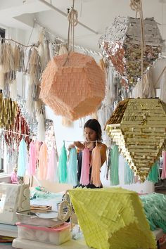 a woman standing in front of a table filled with lots of different colored paper decorations