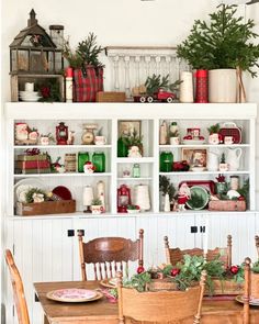 a dining room table and chairs with christmas decorations on the shelves above it, along with other holiday decor