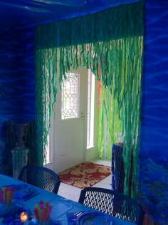 a room decorated in blue and green with streamers hanging from the ceiling, along with a table set for four