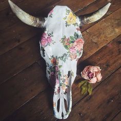 a cow skull with flowers on it and a flower in the foreground next to it