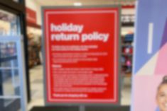 there is a sign that says holiday return policy on the front and side of it