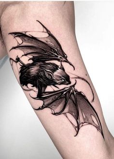 a black and white photo of a dragon tattoo on the right leg, with wings spread out