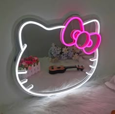 a hello kitty mirror with a pink light on it's face and flowers in the background