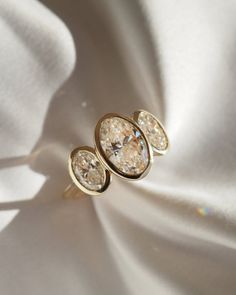 three diamond earrings sitting on top of a white cloth