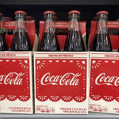 several bottles of coca - cola sit on display in a store shelf, with the lids slightly open