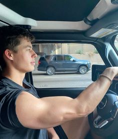 a man sitting in the driver's seat of a car with his hand on the steering wheel