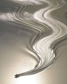 the sun shines through some wavy lines in the sand on the beach at low tide