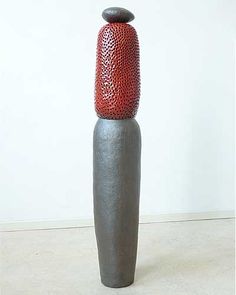 a tall metal vase sitting on top of a white floor next to a red object