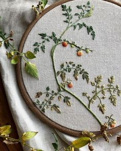 a close up of a embroidery on a piece of cloth with leaves and flowers in it