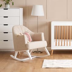 a white rocking chair next to a baby crib