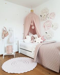 a bedroom with pink and white decor on the walls, bedding and rugs