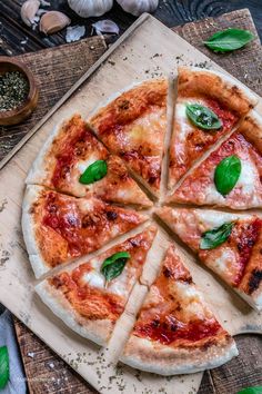 two pizzas with different toppings sitting on cutting boards next to tomatoes and garlic