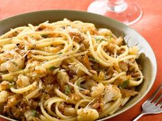 a bowl filled with pasta and meat on top of a table next to a glass of wine