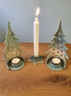 two candles are sitting next to each other in front of a christmas tree candle holder