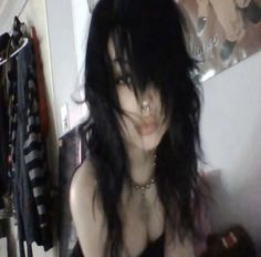 a woman with long black hair and piercings on her chest posing for the camera