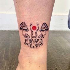 a woman's foot with a tattoo on it that has two mushrooms and a red dot in the middle