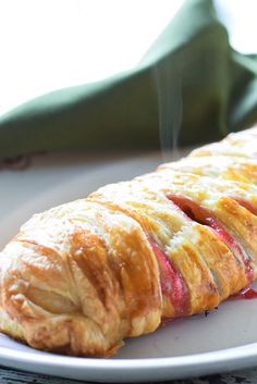 a pastry on a white plate next to a green napkin