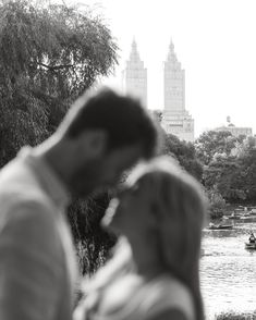 a man and woman standing next to each other in front of a body of water