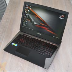 an asus laptop computer sitting on top of a wooden table next to a mouse