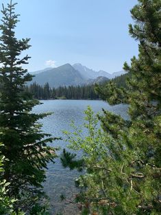 a lake surrounded by trees with mountains in the background