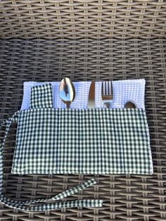 a green and white checkered cloth with silverware in it on a wicker table