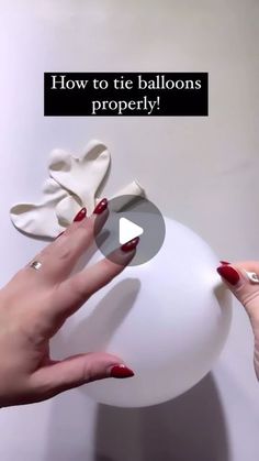 a woman's hands holding a white ball with hearts on it and the words how to tie balloons properly