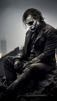 a man dressed as the joker sitting on top of a pile of rocks in front of a cityscape