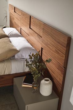 a bed with white sheets and pillows on top of it next to a vase filled with flowers